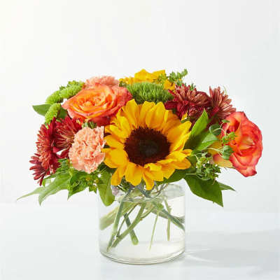 Mixed bouquet with a sunflower, roses, and chrysanthemums in a glass vase