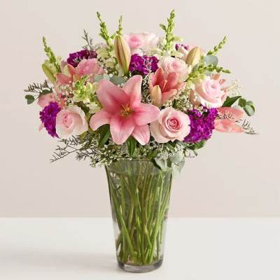 Pink lilies and roses arranged in a clear glass vase