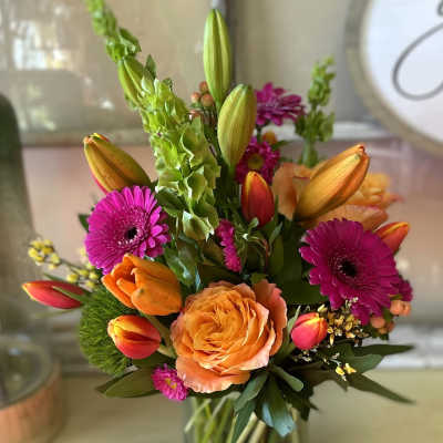 Colorful bouquet of tulips, roses, and gerbera daisies in a glass vase