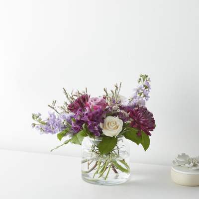 Mixed pink, purple, and white flowers in a clear glass vase