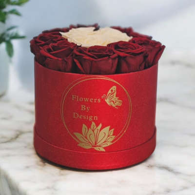 Red roses arranged in a round red box with a white rose center