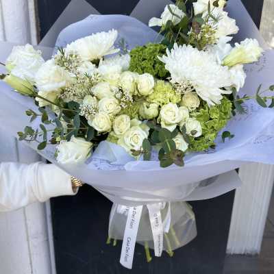 White bouquet with roses, chrysanthemums, and green hydrangea in pale wrapping