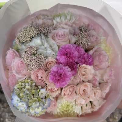 Pastel bouquet of pink roses, carnations, and hydrangea wrapped in pink paper