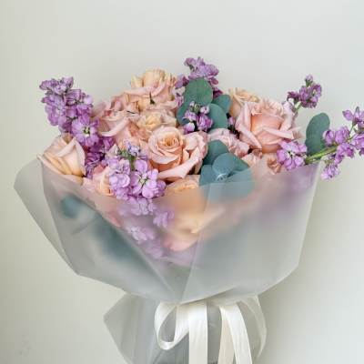 Bouquet of blush roses and purple flowers in a glass vase