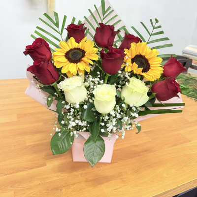 Bouquet of red and white roses with yellow sunflowers in a pink box
