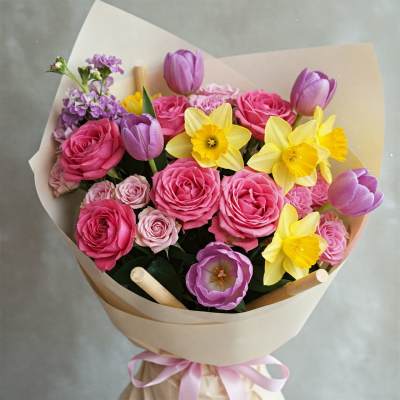 Bouquet of pink roses, purple tulips, and yellow daffodils wrapped in paper