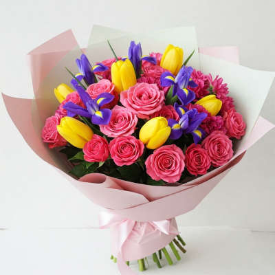 Bouquet of pink roses, yellow tulips, and purple irises wrapped in pink paper