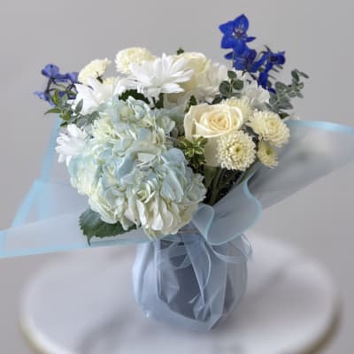Bouquet of white and pale blue flowers in a wrapped vase