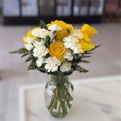 Yellow roses and white carnations in a clear glass vase