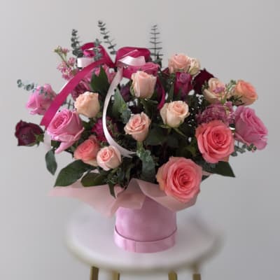 Pink and peach roses arranged in a pink box with ribbon