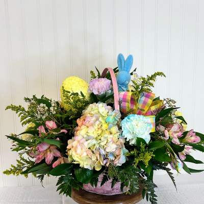 Pastel Easter basket arrangement with hydrangeas, carnations, alstroemeria, eggs, ribbon, and a plush bunny.