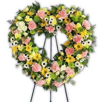 Heart-shaped floral wreath on a stand with pink, yellow, white, and green flowers
