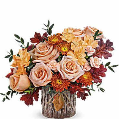 Autumn bouquet of peach roses and orange mums in a rustic wood vase