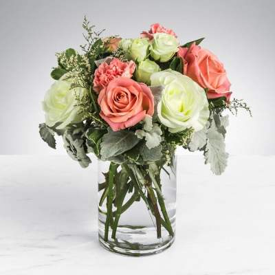 Peach and pale green roses with pink carnations in a clear glass cylinder vase