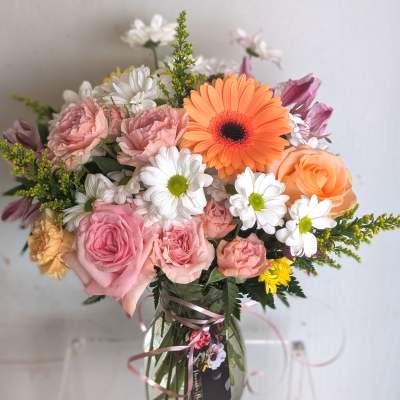 Mixed bouquet of pink roses, white daisies, and an orange gerbera daisy in a clear glass vase