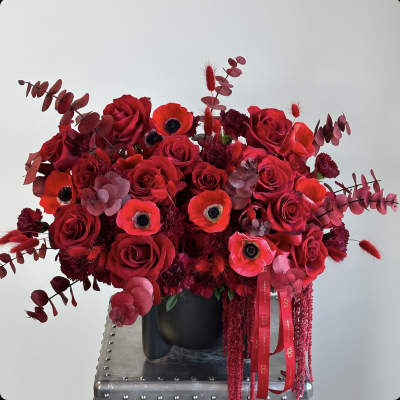 Red rose bouquet with poppies in a black vase