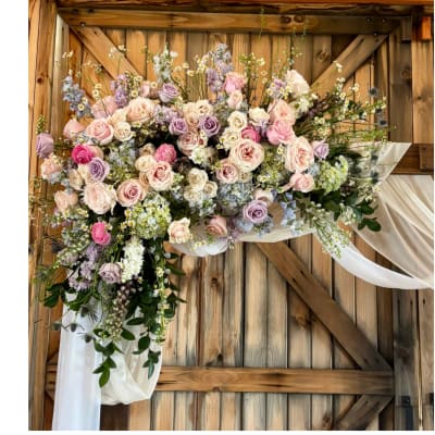 Large pastel floral arrangement with roses and draped white fabric