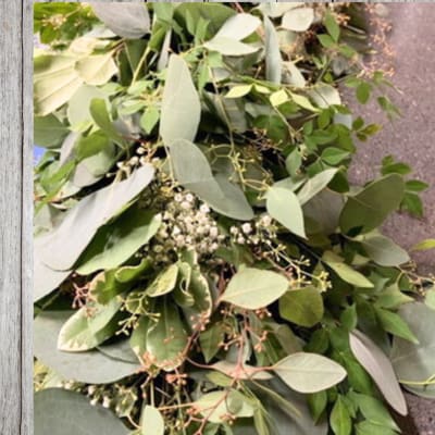 Loose bundle of assorted green foliage with small white filler flowers