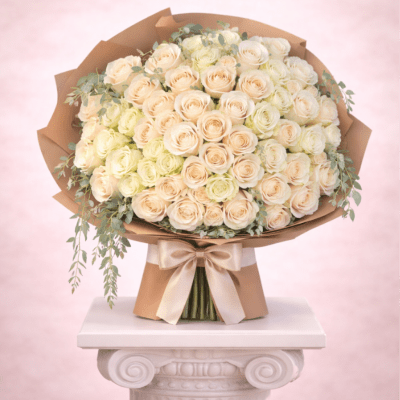 Large bouquet of cream and blush roses wrapped in brown paper with a satin bow
