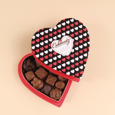 Heart-shaped box of assorted chocolates with a patterned lid of red and white hearts.
