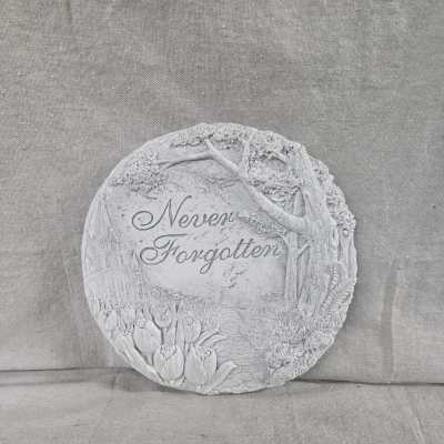 Round gray memorial stone plaque with carved scene and the words Never Forgotten