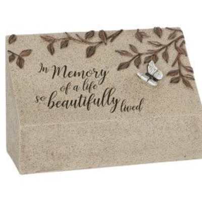 Beige memorial stone block with leaf accents, silver bird, and script remembrance text.