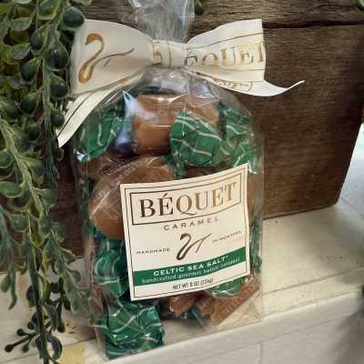 Bag of caramel candies tied with a ribbon beside faux greenery