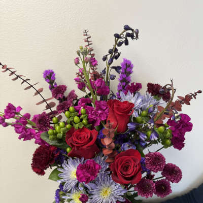 Bouquet of red roses, purple blooms, and lavender daisies