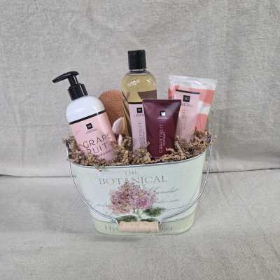 Grapefruit-scented bath gift set arranged in a floral metal pail with crinkle paper filler
