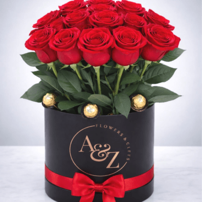 Red roses arranged in a black hatbox with a red ribbon and chocolates
