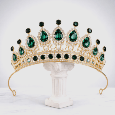 Gold tiara with green gemstones on a white pedestal