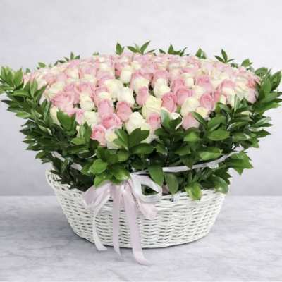 Pink and white roses in a white wicker basket with a ribbon