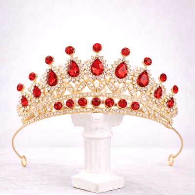 Gold tiara with red gemstones on a white stand
