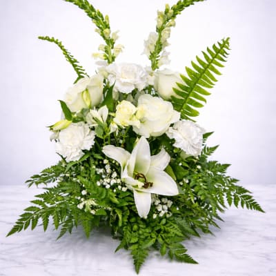 White floral arrangement with lilies, roses, and ferns