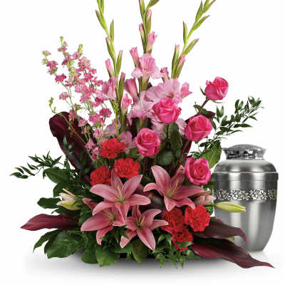Pink lilies, roses, and carnations arranged beside a silver urn