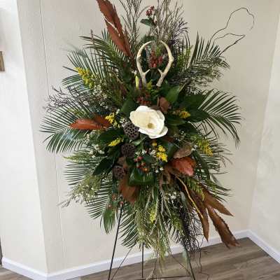 Tall floral standing spray with white bloom and mixed greenery on an easel
