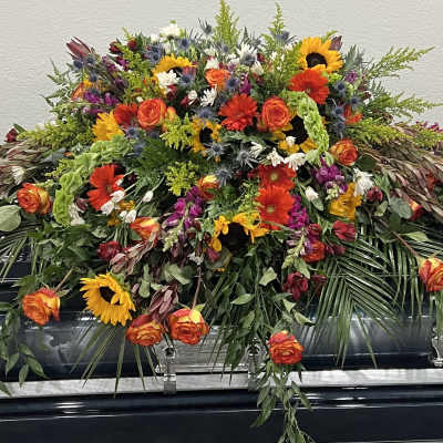 Large floral casket spray with sunflowers, roses, and mixed blooms