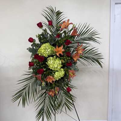 Standing floral spray with red roses, orange lilies, and green hydrangeas