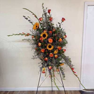 Tall floral spray with sunflowers and orange roses on a stand