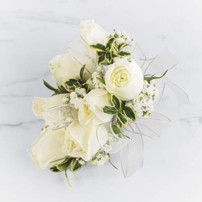 Small cluster of white roses with white filler flowers and sheer ribbon in a compact design
