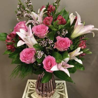 Pink roses and white lilies in a pink glass vase
