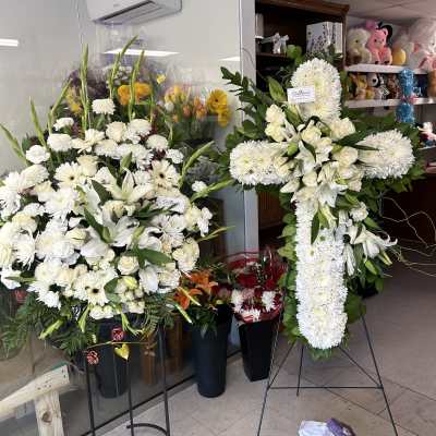 Large white funeral floral stands with lilies and chrysanthemums