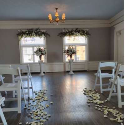 Wedding aisle with white chairs, flower petals, and tall floral stands