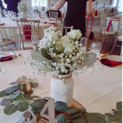 White floral centerpiece in a mason jar on a decorated table
