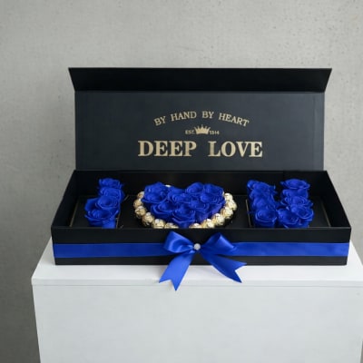 Blue roses arranged in a black gift box with a ribbon bow