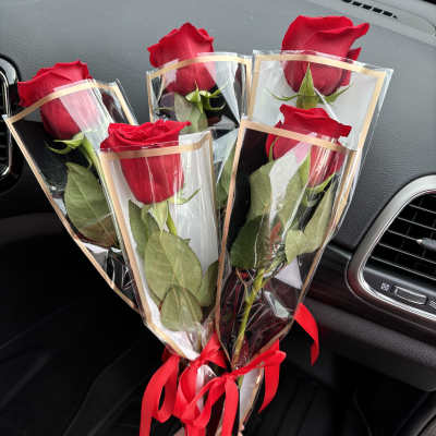 Four red roses wrapped in clear plastic with red ribbons