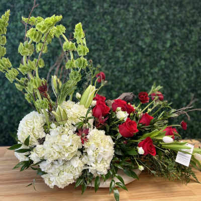 Low floral arrangement with white hydrangeas, red roses, and tall green blooms