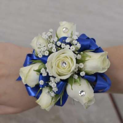 White rose wrist corsage with blue ribbon and rhinestone accents