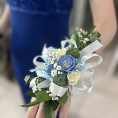 Small wrist corsage with blue and white roses and ribbon