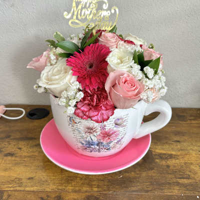 Pink and white flower arrangement in a teacup with a Mother's Day topper